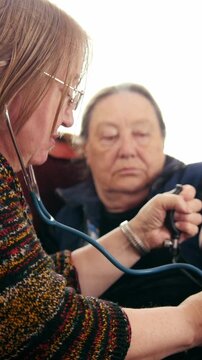 Two pensioners - senior ladies checking healthcare state with manometer - measures pressure, elderly lifestyle