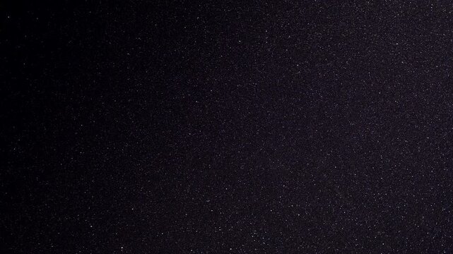 Densely Packed Amber Glitter Dust Drifting over Black Surface