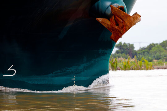 Close-up of a large cargo ship bow with rusty anchor navigating a tropical river.  Vung Tau. Vietnam.