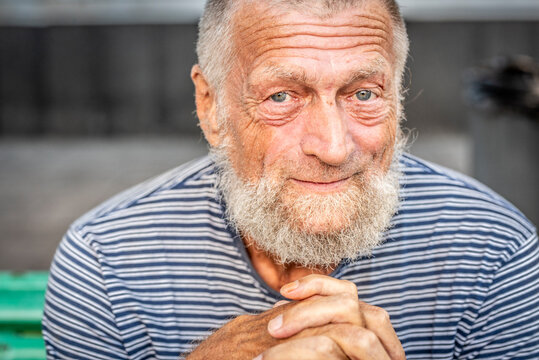 Elderly man with beard smiling in casual striped shirt outdoor portrait showing warm expression