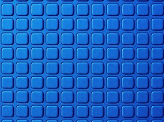 Fototapeta premium Textured blue rubber surface pattern with repeating rounded square shapes