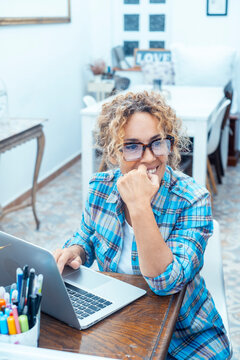 Woman working remotely on laptop at home office smiling while planning and thinking creatively