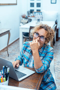 Woman working on laptop in bright home office smiling while planning and studying