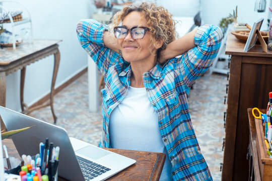 Relaxed woman stretching at her home office laptop after focused remote work session