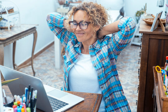 Relaxed woman taking a break from remote work at her home desk with a laptop