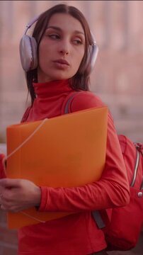 Carefree university student dancing with headphones at sunset
