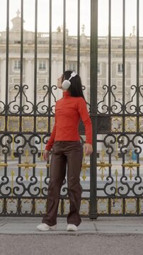 Joyful woman dancing with headphones in Madrid royal palace