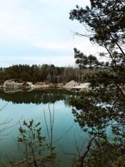 Fototapeta premium Peaceful forest lake with pine trees and clear water reflection