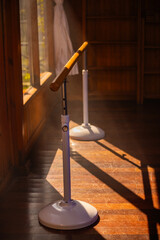 Ballet barre in dance studio with wooden parquet floor and shadows from morning sun.