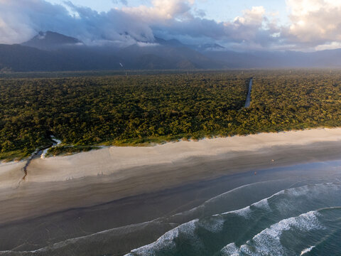 Aerial wide view of Bora Bora beach in Boraceia at sunset with people walking on wet sand mirror in Brazil