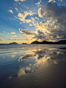 Cinematic wide shot of Baleia beach at sunset with dramatic colorful clouds and perfect reflection on wet sand