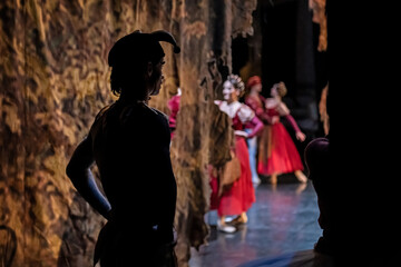 Obraz premium Male dancer in jester hat backstage watching female performers