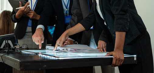 Fototapeta premium Business team planning project, hands pointing at documents on a table. Concept of corporate collaboration, strategic data analysis, and professional teamwork during a creative meeting