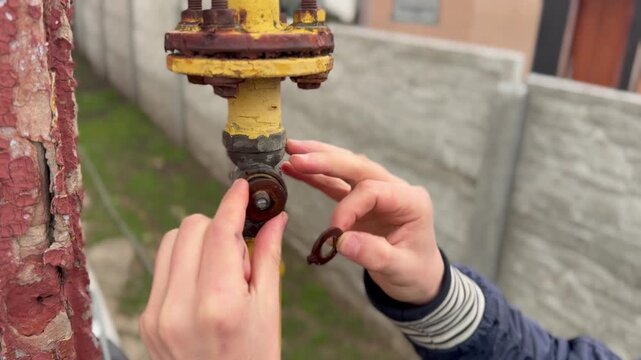 Gas fitter hands removing old gaskets from outdoor gas valve