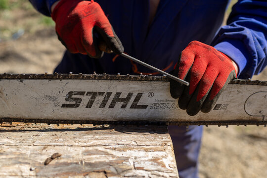 Detailed view of a STIHL chainsaw blade being sharpened manually, suitable for editorial content about safety, maintenance, and woodworking techniques.