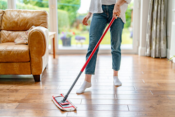 Fototapeta premium Person mopping wooden floor in living room during daytime while wearing socks