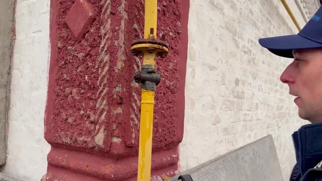 Gas fitter closing valve on outdoor pipe to fix gas leak