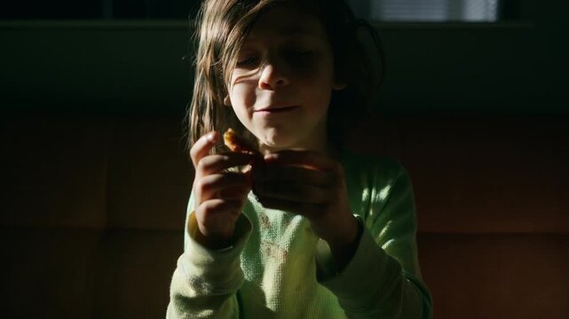 Boy with a messy face eating pizza on movie night
