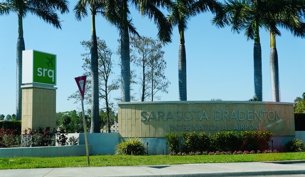 Sarasota, Florida, U.S.A - March 27, 2026 - The Sarasota Bradenton International Airport entrance featuring a stone monument sign and a tall green SRQ logo.