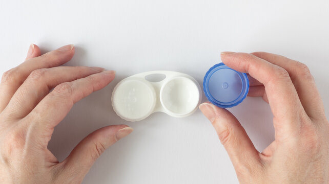 Human hands unscrew the lid of a contact lens case