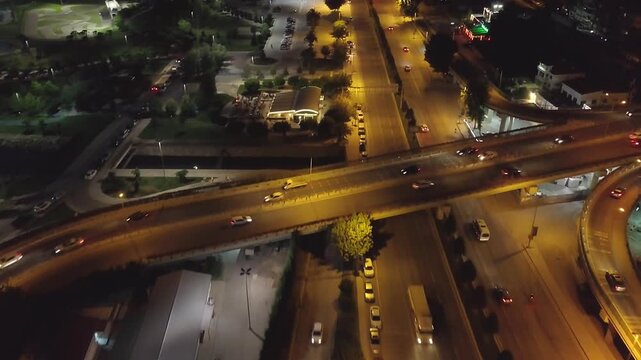 Aerial time lapse of night traffic on Maltepe coastal highway overpass junction with golden street lights and light trails, Istanbul