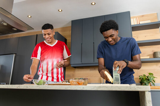 Cooking Diverse male friends mixing and grating zest on marble kitchen island, with glass bowls