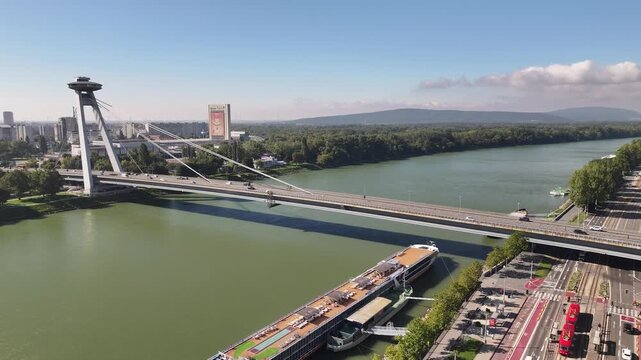 Aerial drone view of the SNP Bridge, UFO observation deck, Danube river and red trams in Bratislava, Slovakia.