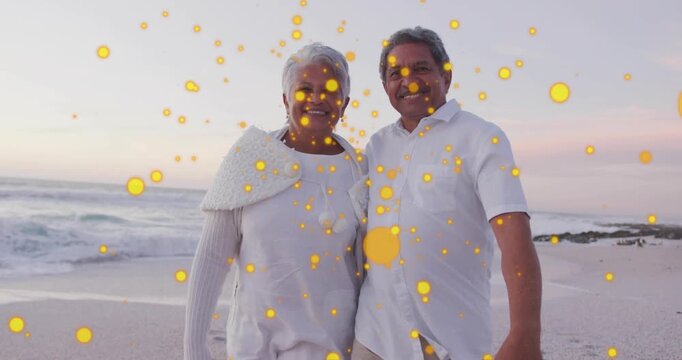 Seniors walking on dusk sea, camera zooming, gold bokeh drifting, pausing, posing, promoting travel