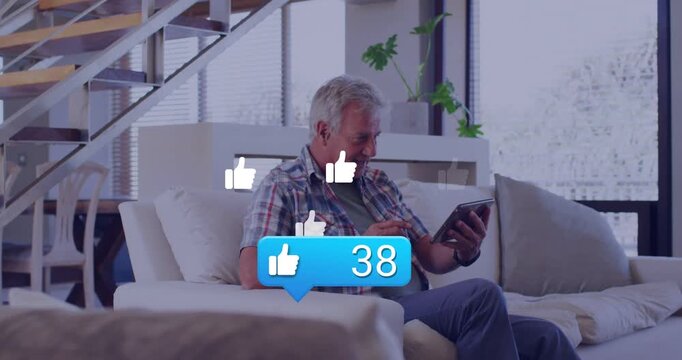 Senior man tapping tablet at home, causing like counter, rising thumbs, driving social media growth
