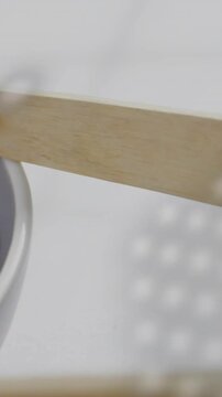 Vertical video: Wooden spatula entering frame, revealing salad as mesh casting overlay for plating