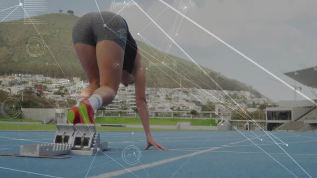 Female athlete pushing through blocks on blue track accelerating after signal with data overlays