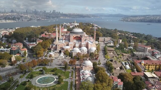 Close aerial view of Hagia Sophia mosque with Sultanahmet Square fountain garden tourists and Topkapi Palace, Bosphorus skyline in background, Istanbul