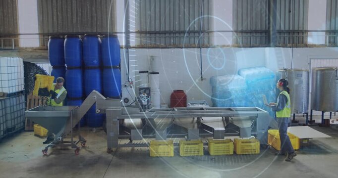 Man feeding crate into hopper producing overlays and woman using laptop optimizing plant sorting