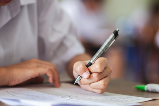 Close-up of a Student's Hand Writing an Exam on Answer Sheet