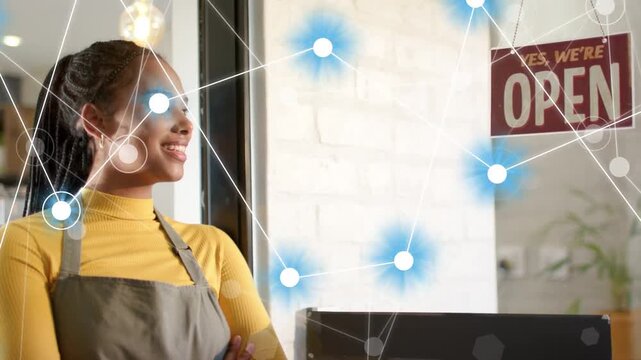 Vertical video: Pulling back camera showing woman standing in apron at shop, OPEN sign, network