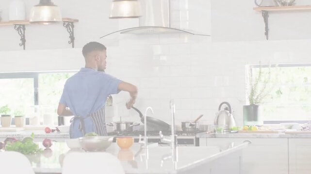 Home cook facing stove and stirring frying pan with spatula, showing culinary prep on island