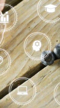 Vertical video: Hand placing blueberry bowl on wood HUD icons floating for food ads camera panning
