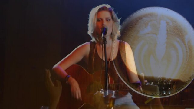 Woman singer strumming guitar singing to music fans camera steadying and spotlight overlapping her