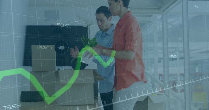 Pair entering with boxes and arranging office, placing orchid while finance graph overlaying