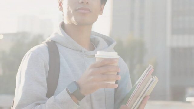 Vertical video: Adjusting grip man in hoodie lifting cup smelling sipping coffee on roof with notes