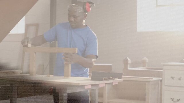Vertical video: Sun revealing man blue shirt muffs aligning sanding top with block for fit at bench