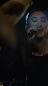 Vertical video: Female singer starting concert, singing into mic, engaging crowd hands and lights