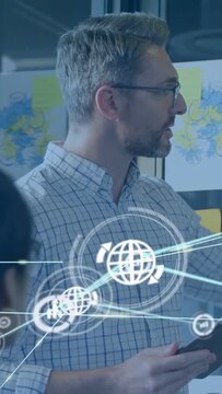 Vertical video: Presenter tapping tablet starting network HUD over glass postits, showing tech data