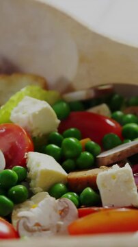 Vertical video: Salad bowl revealing spoon, tomato as camera panning, grid drifting for food ads