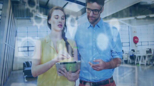 Woman demoing system, tapping tablet and starting tech nodes and rings, man leaning and nodding