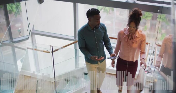 Vertical video: Team descending stairs in office tapping tablet showing animated charts for review
