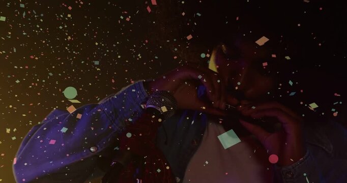 Vertical video: Male singer at mic making heart while cue releasing confetti thanking music fans