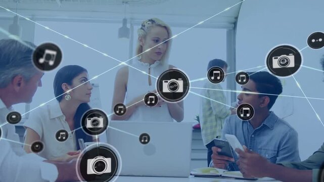 Vertical video: Diverse team around table watching blond lead tapping laptop, adding icons for demo