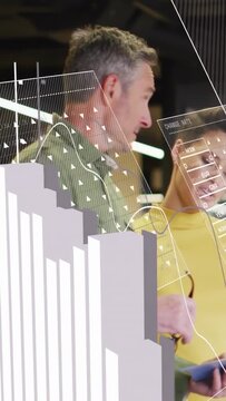 Vertical video: Woman in yellow showing tablet, man leaning analyzing finance data with charts