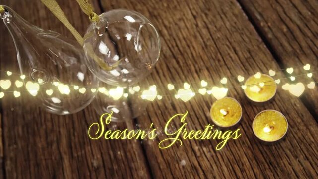 Animation of text, season's greetings, in yellow, string lights, candles and christmas decorations